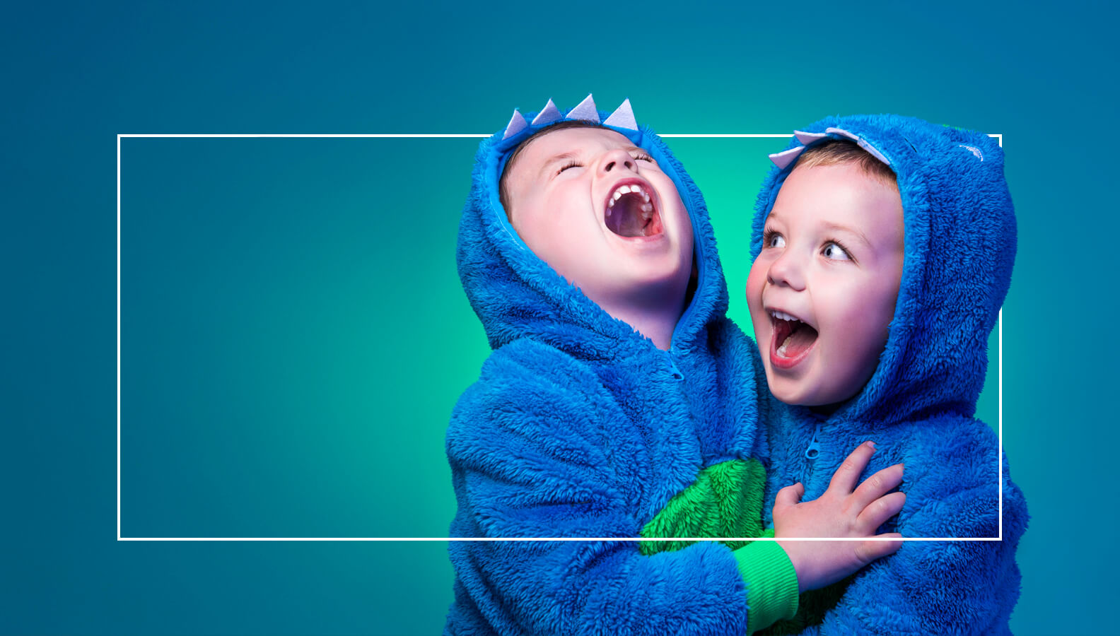 Child portrait of two brothers laughing and smiling in dinosaur onesies