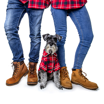 a couple and a dog wearing matching plaid shirts