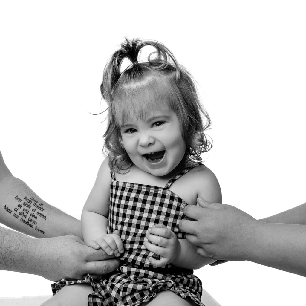 a black and white image of a young girl being tickled