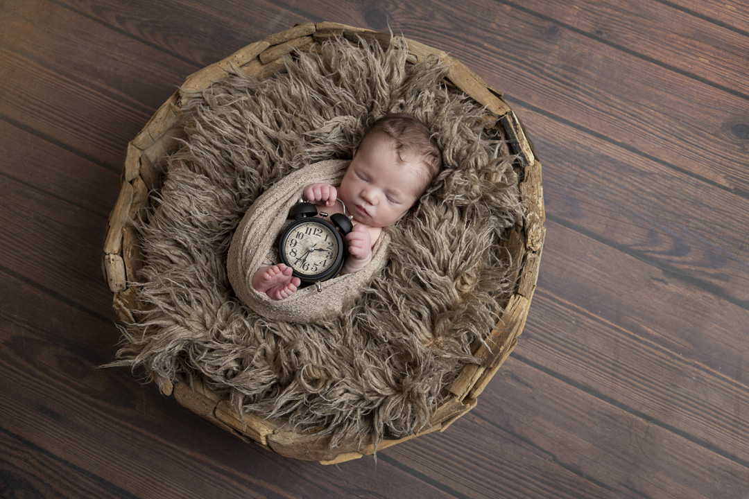 A newborn baby nestled in a blanket inside a basket