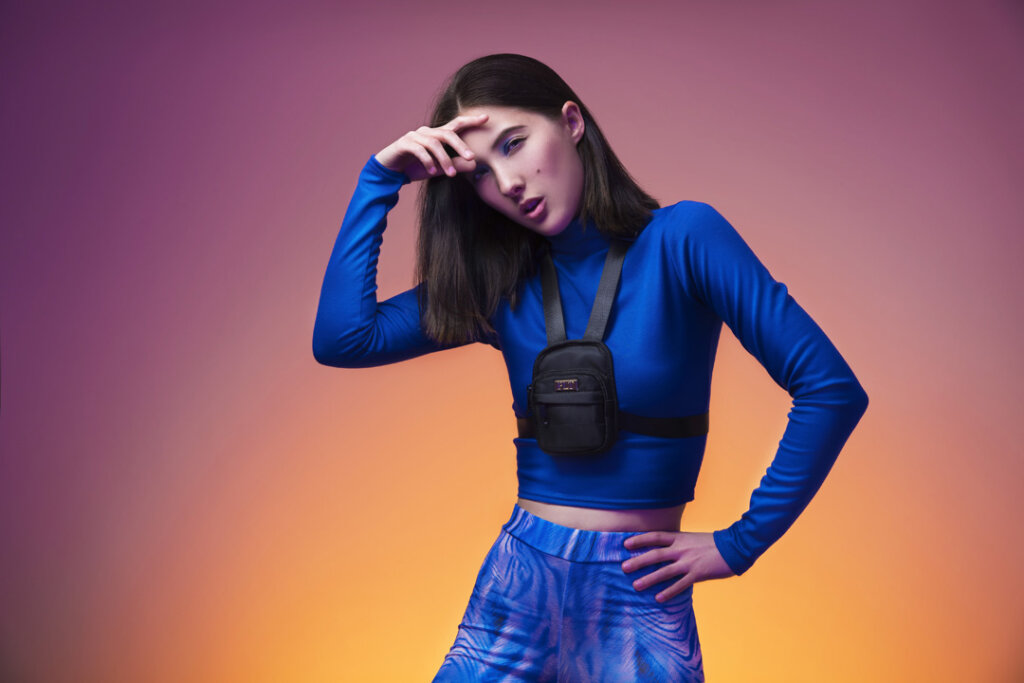 A model wearing blue clothing against a purple and yellow background