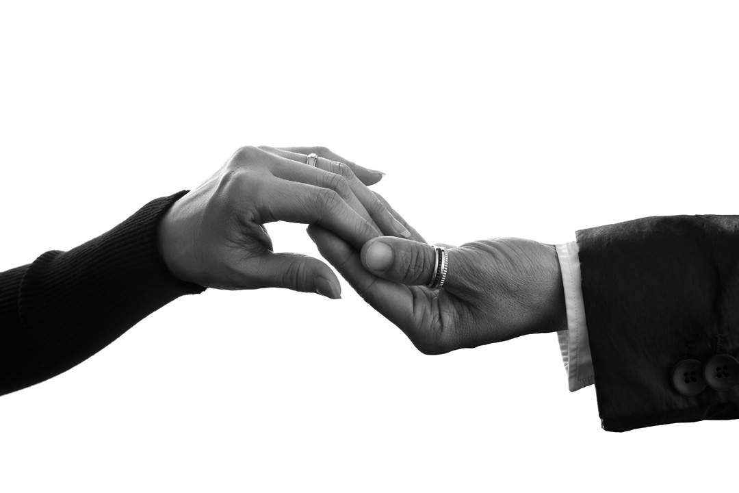 A close up photograph of a couple touching hands