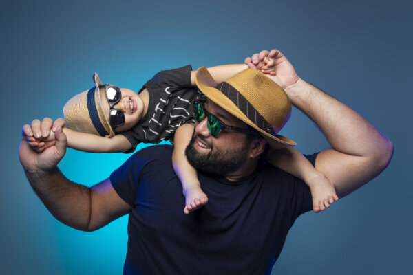 A son riding on his dad's shoulders on a blue background