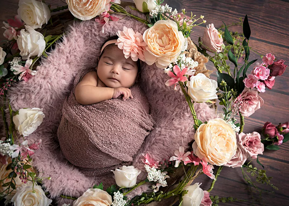 Sleeping new born baby surrounded by flowers
